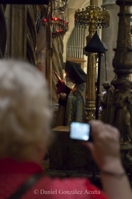 Turista fotografiando a un sacerdote ortodoxo en el Santo Sepulcro